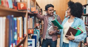 Two diverse students select cultural content from library