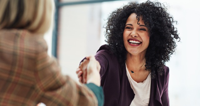 Woman shakes another person's hand while smiling