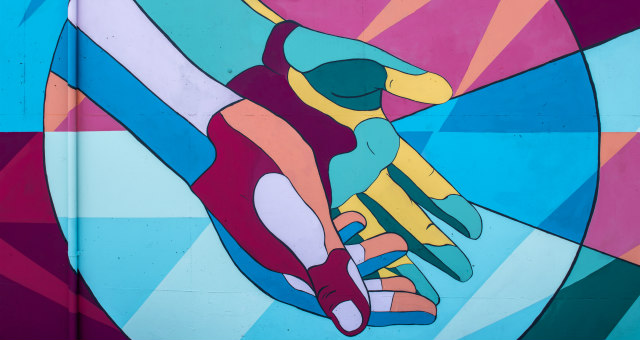 Multi-colored hands on graffiti wall