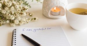 notebook says "I'm grateful for..." with candle and tea in background