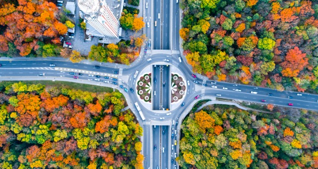 Roundabout features cars driving during fall and fall colored trees