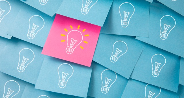 Sticky notes with light bulbs on them has one pink colored one that sticks out with light bulb lit up