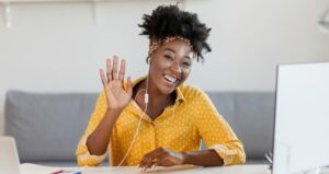 Teacher waving with headphones and computer