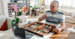 Senior citizen plays backgammon against someone on computer on Zoom call