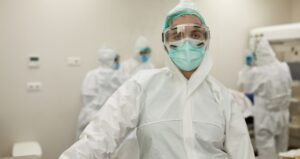 Healthcare worker wears gear and masks while looking exhausted