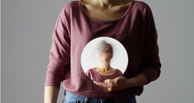Person holds mirror with blurred identity