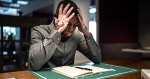 Student puts hands on head while reading book in distress