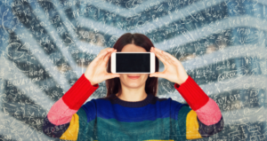 Woman wearing a rainbow shirt holding a cellphone in front of her face