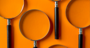 On an orange background, four magnifying glasses are displayed