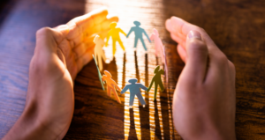 Hands surrounding multicolored paper- people.