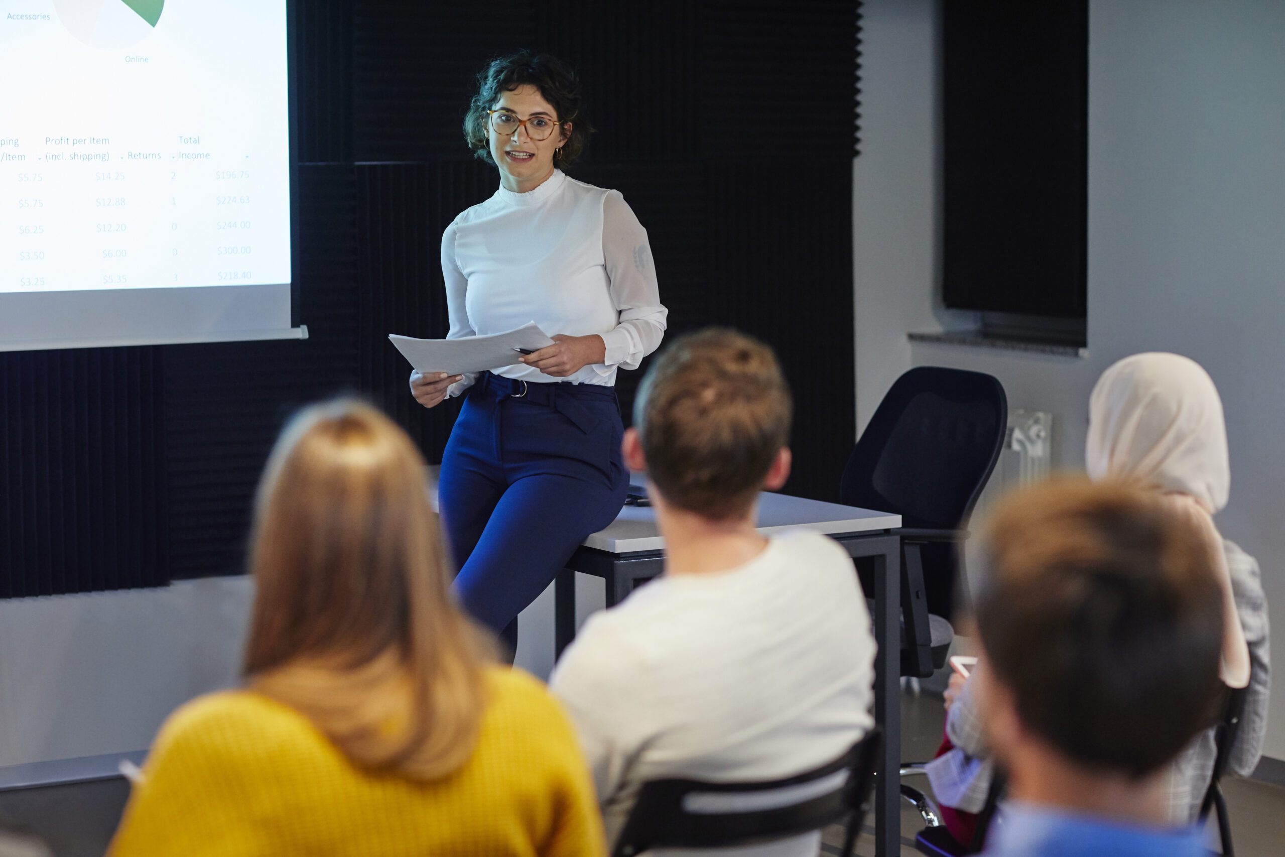 Presentation with team. Young woman have presentation in conference room. Sitting and talking in front of projection screen.