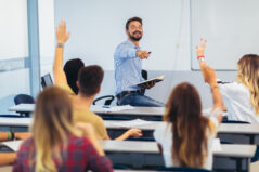 Group of students raising hands in class on lecture