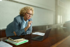 Female professor brainstorming while reading lecture plans on a computer in the classroom. Copy space.
