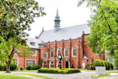 Exterior of private liberal arts Huntingdon College building in Alabama with old, brick, historic architecture, green park, clock