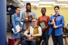 Vibrant portrait of diverse group of students in college young man with disability in foreground all looking at camera