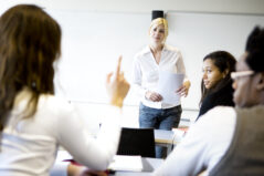 further education: teenager asking her teacher a question in class