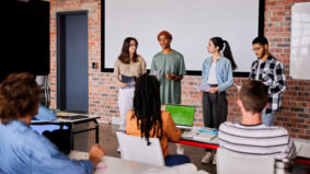 Diverse group of students giving a presentation to their classmates during a lesson at a school