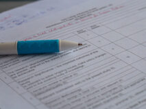 A macro (closeup) of a white pen with blue rubber on a paper with grading questions on it