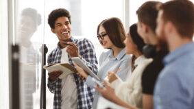 College students laughing, solving problems on whiteboard and taking notes