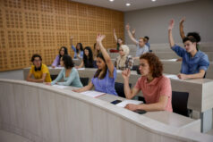 Student engagement and participation. Group of college students raising their hands and asking a question to the teacher in class - education concepts