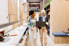 Peer Coaching. Modern female professors talking about something at the library.