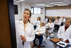 Teacher writing on the board while teaching a class to a group of Latin American medical students - education concepts