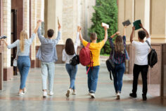 Happy students raised hands and walking in college campus. Showing happiness, success, support.
