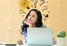 Idea light bulbs with question marks with young woman using a laptop. online courses.