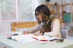 Young woman taking notes while studying at home