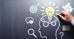 Drawing lightbulb and head silhouette on chalkboard. Focus on students and developing skills. Deeper learning.