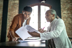 Teacher helping student on his desk, giving feedback on assignment