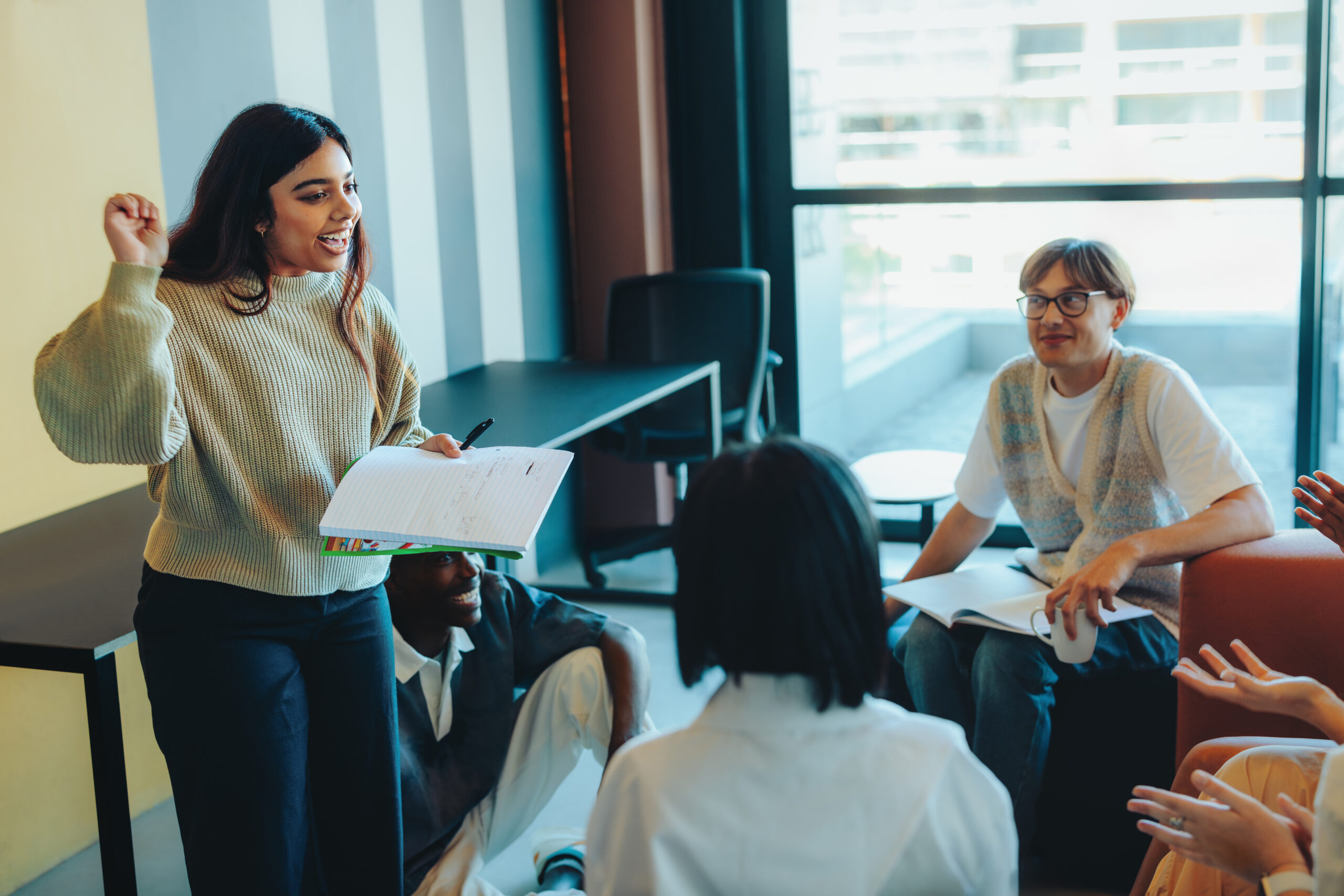 A student confidently presents a project to classmates in a modern classroom environment, with an engaged and attentive audience.