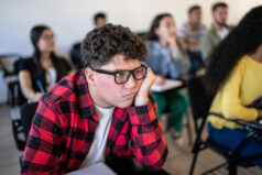 Bored young man watching class at university. Difficult student.