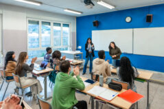 Multi-ethnic university students clapping their hands after a presentation by two classmates in a modern classroom. Safety and experiential learning.