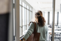 A rear view of a female professor holding the door as she enters her empty classroom before her students arrive.