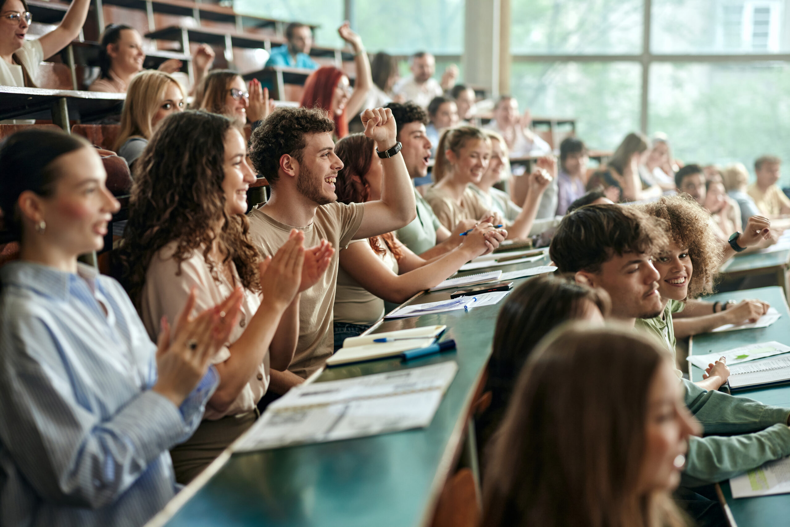 Crowd of cheerful university students having fun while applauding on a class at amphitheater. Engaging learning experience.
