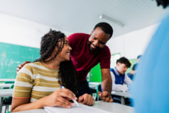 Teacher assisting teenager student during class in classroom