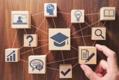 Putting wood cubes with educational icons. Top view of wood table. Demonstrating cross-disciplinary collaboration in higher education.